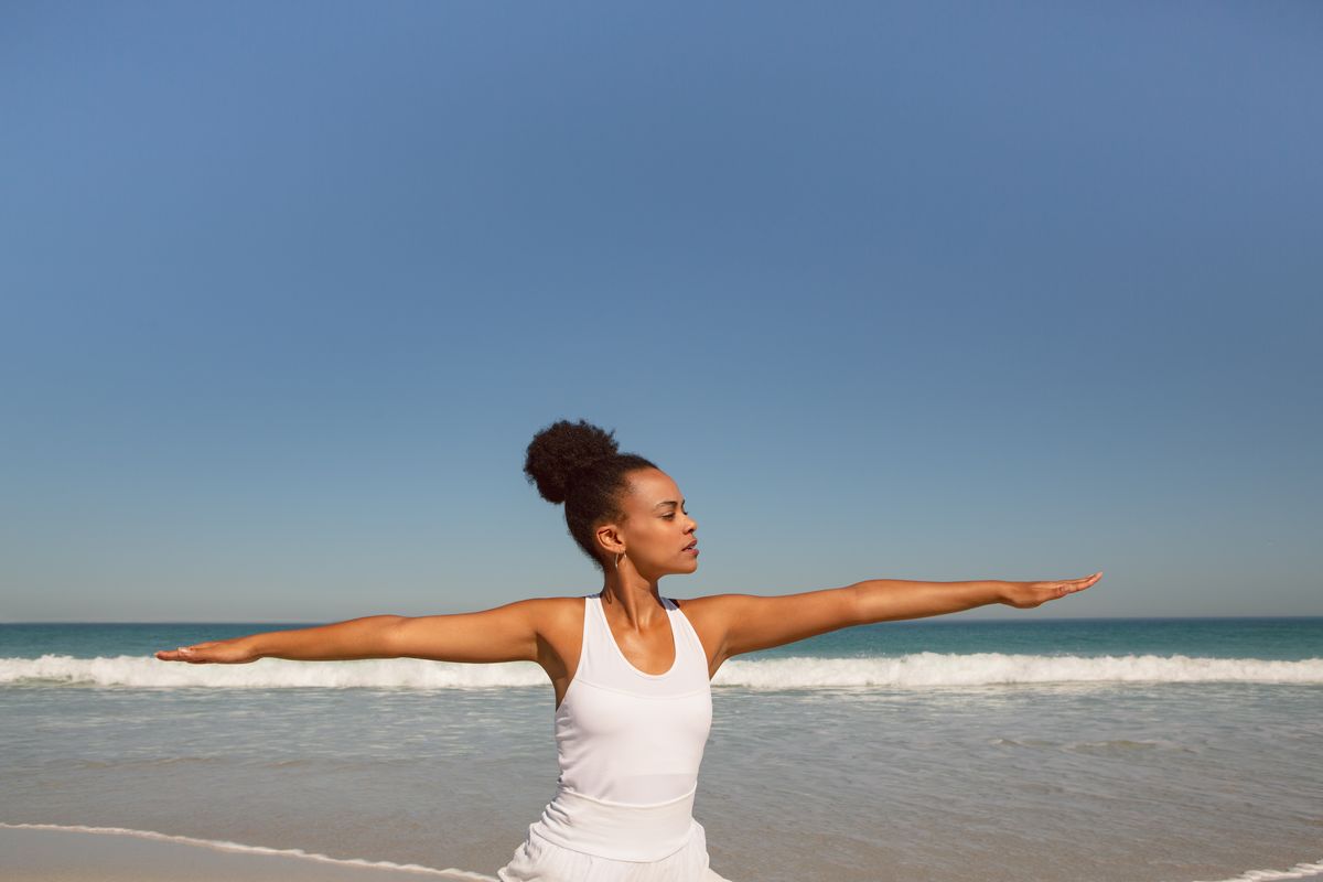 Front view of beautiful African american woman doing yoga at beach in the sunshine association femmes Guadeloupe